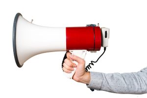 Hand of man holding shouting by megaphone